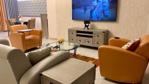 a living room with orange chairs and a tv at The African Palace- Free Airport Pick up - High Speed Starlink WiFi - Car Rental in Tamale