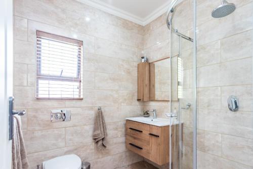 a bathroom with a shower and a toilet and a sink at 150 Jacaranda Guesthouse in Midrand