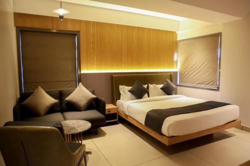 a bedroom with a bed and a couch at RAGA - A Boutique Hotel in Belgaum