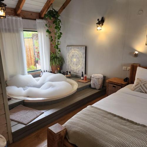 a bedroom with a large white tub in a window at ברוגע אצל נוגה סוויטה עם בריכה פרטית in Moshav Ramot