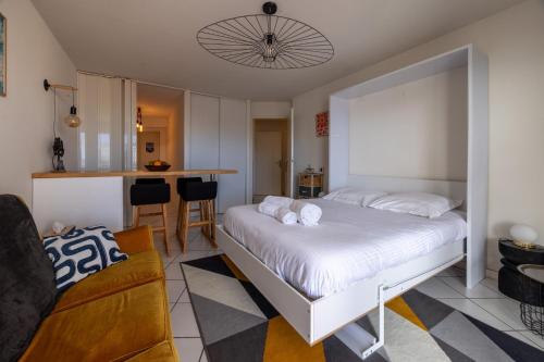 Cet appartement comprend une chambre avec un lit blanc et une cuisine. dans l'établissement Bassin Bleu - Vue sur le port d'Arcachon, à Arcachon