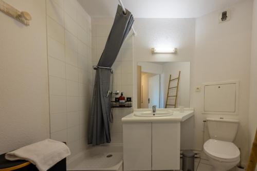 une salle de bain blanche avec un lavabo et des toilettes dans l'établissement Bassin Bleu - Vue sur le port d'Arcachon, à Arcachon