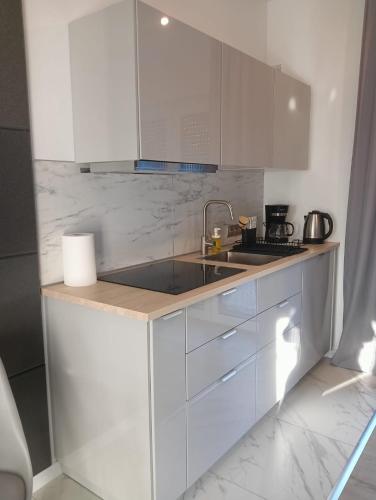 a kitchen with white cabinets and a sink at Apartament Jana Pawła in Głogówek