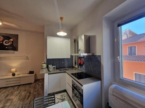 a kitchen with white cabinets and a large window at Grosseto Design Apartment in Grosseto