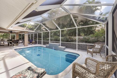 a swimming pool in a house with a large glass wall at Quiet inland home with pool, two queen beds and grill in Marco Island
