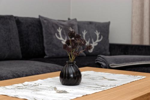 a black vase with flowers on a table at Appart-Hotel Wildererstuben in Bodenmais