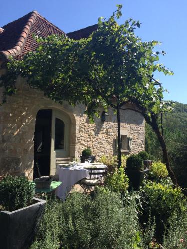 a stone house with a table in the garden at Le Mas de Laval in Saint-Cirq-Lapopie