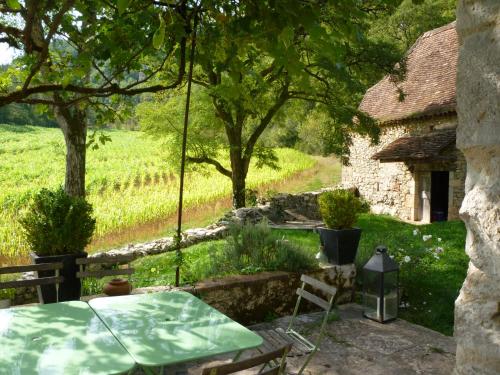 a garden with a table and chairs and a house at Le Mas de Laval in Saint-Cirq-Lapopie