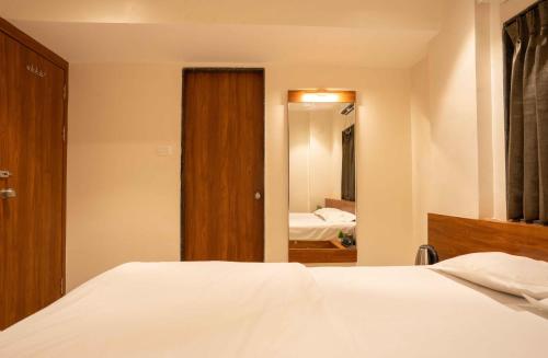 a bedroom with a bed and a door with a mirror at Majestic Inn in Pune