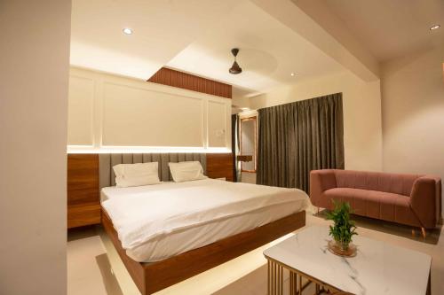 a bedroom with a bed and a pink couch at Majestic Inn in Pune