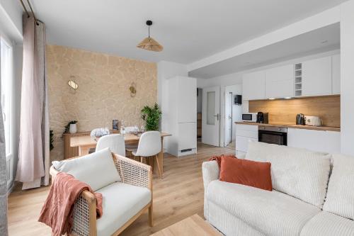 a living room with a couch and a table and a kitchen at Appartement confortable et élégant en centre ville in Rouen