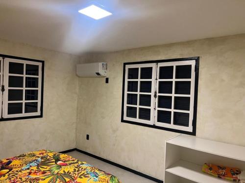 a bedroom with a bed and two windows at Casa estilosa na rua principal de Búzios in Búzios