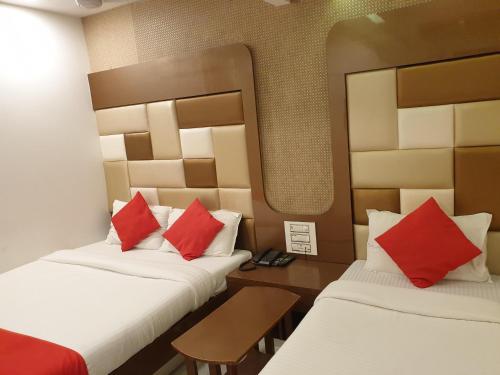 zwei Betten in einem Hotelzimmer mit roten Kissen in der Unterkunft Hotel Gulf in Mumbai