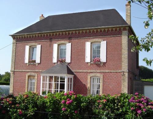 a red brick house with white windows and flowers at Gîte familial à la ferme des Hellandes in Angerville-lʼOrcher