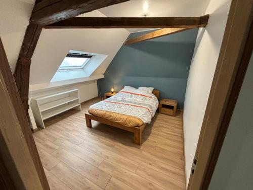 a attic room with a bed and a window at Gîte familial à la ferme des Hellandes in Angerville-lʼOrcher