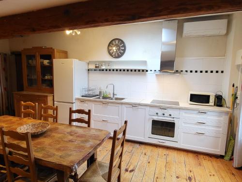 a kitchen with white cabinets and a table and a clock at Gite le grenier des maraichers in Albigny-sur-Saone