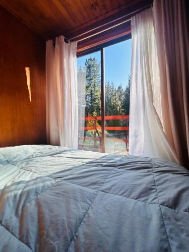 a bedroom with a bed and a large window at Casa Eco Bosque in Pichilemu