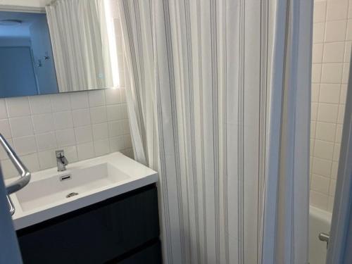 une salle de bain avec un lavabo et un rideau de douche dans l'établissement Appartement T3 avec Piscine, Climatisation et Parking à 350m de la Plage - Capacité 4 Personnes - FR-1-749-34, au Cap d'Agde
