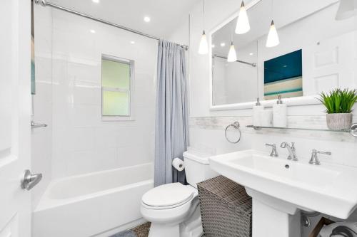 a white bathroom with a sink and a toilet at Renovated 2BR Home - Hot Tub, Gym & Beach Nearby in West Palm Beach