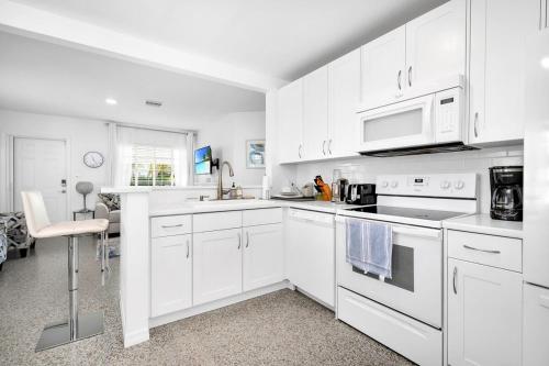 a white kitchen with white cabinets and a microwave at Renovated 2BR Home - Hot Tub, Gym & Beach Nearby in West Palm Beach