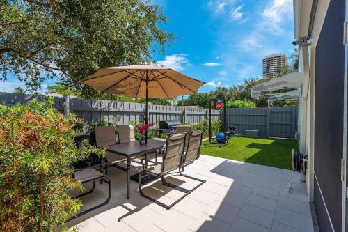 a patio with a table and chairs and an umbrella at Renovated 2BR Home - Hot Tub, Gym & Beach Nearby in West Palm Beach
