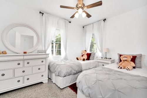 a white bedroom with two beds and a mirror at Renovated 2BR Home - Hot Tub, Gym & Beach Nearby in West Palm Beach