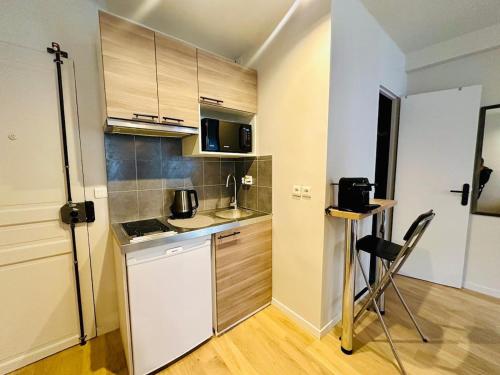 Elle comprend une petite cuisine équipée d'un réfrigérateur blanc et d'une table. dans l'établissement L'Eiffel - Charmant studio proche Tour Eiffel, à Paris