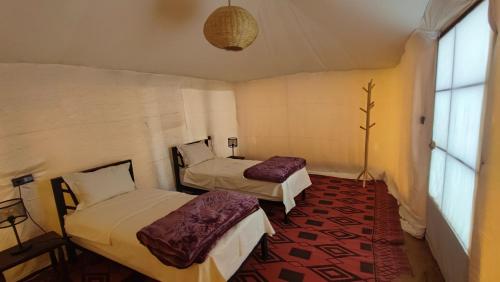 a room with two beds and a window at Touaregs Camp Erg Lihoudi in Mhamid