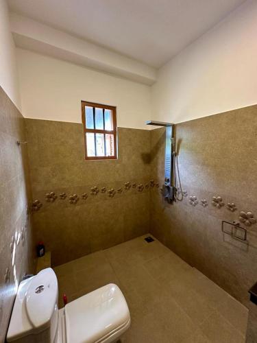 a bathroom with a toilet and a sink and a window at Siyon Yula - Guest House in Hikkaduwa