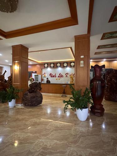 a lobby with a vase and potted plants at Khách sạn Vĩnh Lộc in Lao Cai