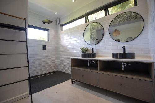 un baño con dos lavabos y dos espejos en Bright and spacious home with private pool, en Ciudad del Cabo