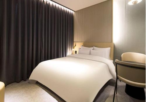 a bedroom with a large white bed and a chair at Day & Night Hotel in Incheon