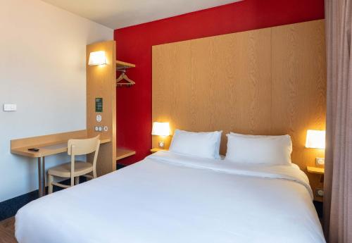 a hotel room with a large bed and a desk at B&B HOTEL Lyon Caluire Cité Internationale in Caluire-et-Cuire