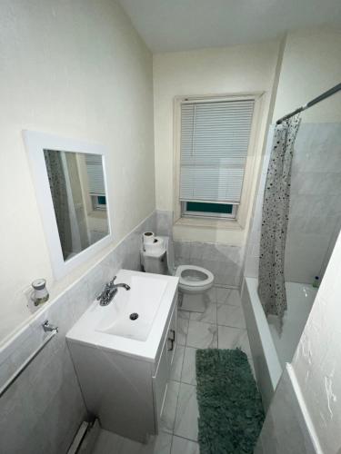 une salle de bain avec un lavabo, des toilettes et un miroir dans l'établissement Esjacpe Guest House, à Boston