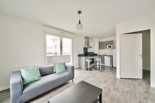 un salon avec un canapé et une cuisine dans l'établissement Havre de paix près de l'Ourcq, à Les Pavillons-sous-Bois