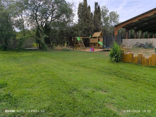 a yard with a playground in the background at Appartement insolite au Ranch Wamakiti in Le Soler