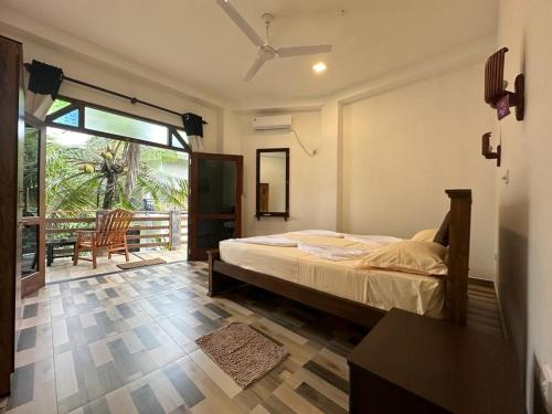 a bedroom with a bed and a sliding glass door at Siyon Yula - Guest House in Hikkaduwa