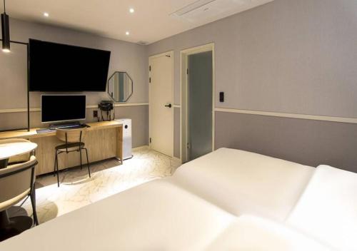a bedroom with a bed and a desk with a computer at Day & Night Hotel in Incheon