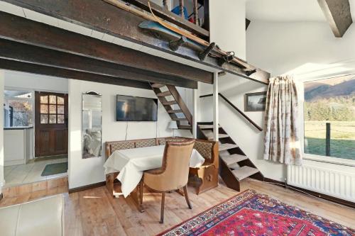 a dining room with a table and chairs and a staircase at Rowan Studio Cottage in Grasmere