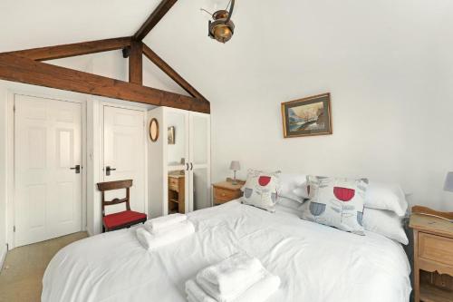a bedroom with a white bed with a red chair at Rowan Studio Cottage in Grasmere