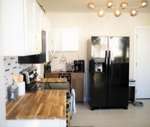 une cuisine avec un réfrigérateur noir et des armoires en bois dans l'établissement Blue Corner Luxe, Timeless Charm Near Downtown, à Little Rock