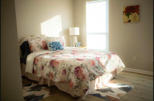 - une chambre avec un lit doté d'un couvre-lit floral et d'une fenêtre dans l'établissement Blue Corner Luxe, Timeless Charm Near Downtown, à Little Rock