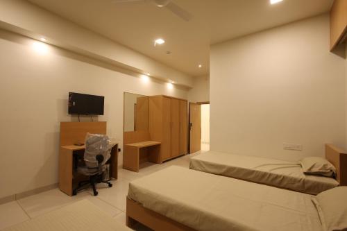 a bedroom with two beds and a desk and a television at Hotel Devbhoomi Prime in Khambhāliya