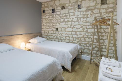 a room with two beds and a stone wall at Gîte 1694 - 4 étoiles - proche Futuroscope in Scorbé-Clairvaux