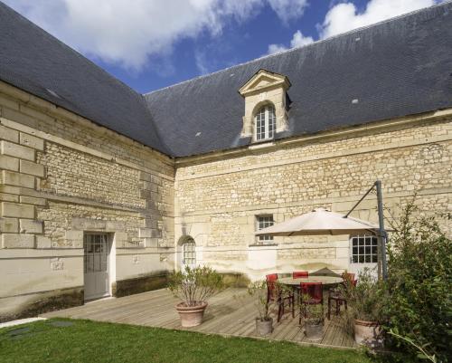 a patio with a table and an umbrella in front of a building at Gîte 1694 - 4 étoiles - proche Futuroscope in Scorbé-Clairvaux