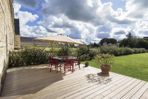 a patio with a table and chairs and an umbrella at Gîte 1694 - 4 étoiles - proche Futuroscope in Scorbé-Clairvaux