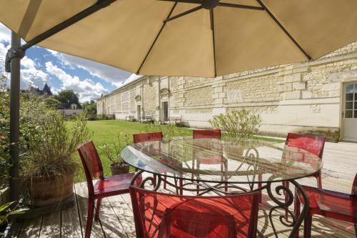 a glass table with chairs and an umbrella on a patio at Gîte 1694 - 4 étoiles - proche Futuroscope in Scorbé-Clairvaux
