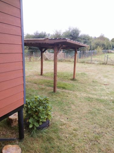 a wooden pergola in a field with a plant at Cabaña Tranquila in Villarrica