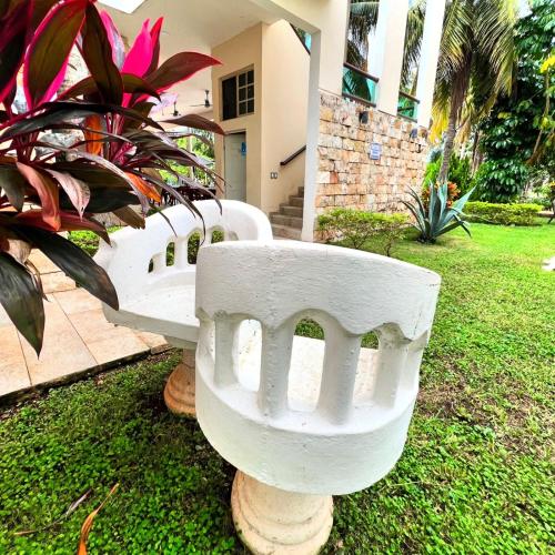 a white bench sitting in the grass in front of a house at Villas Paraíso in Mérida