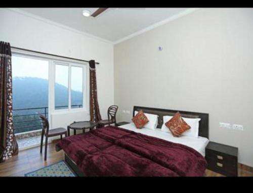 ナイニタールにあるNainigreen Valley Kainchidham Luxurious Homestayのベッドと大きな窓のある寝室